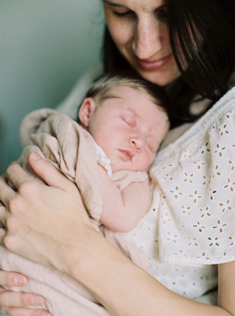Lifestyle newborn photo of a new mom gazing at her baby — capturing early moments and favorite newborn must-haves.”
