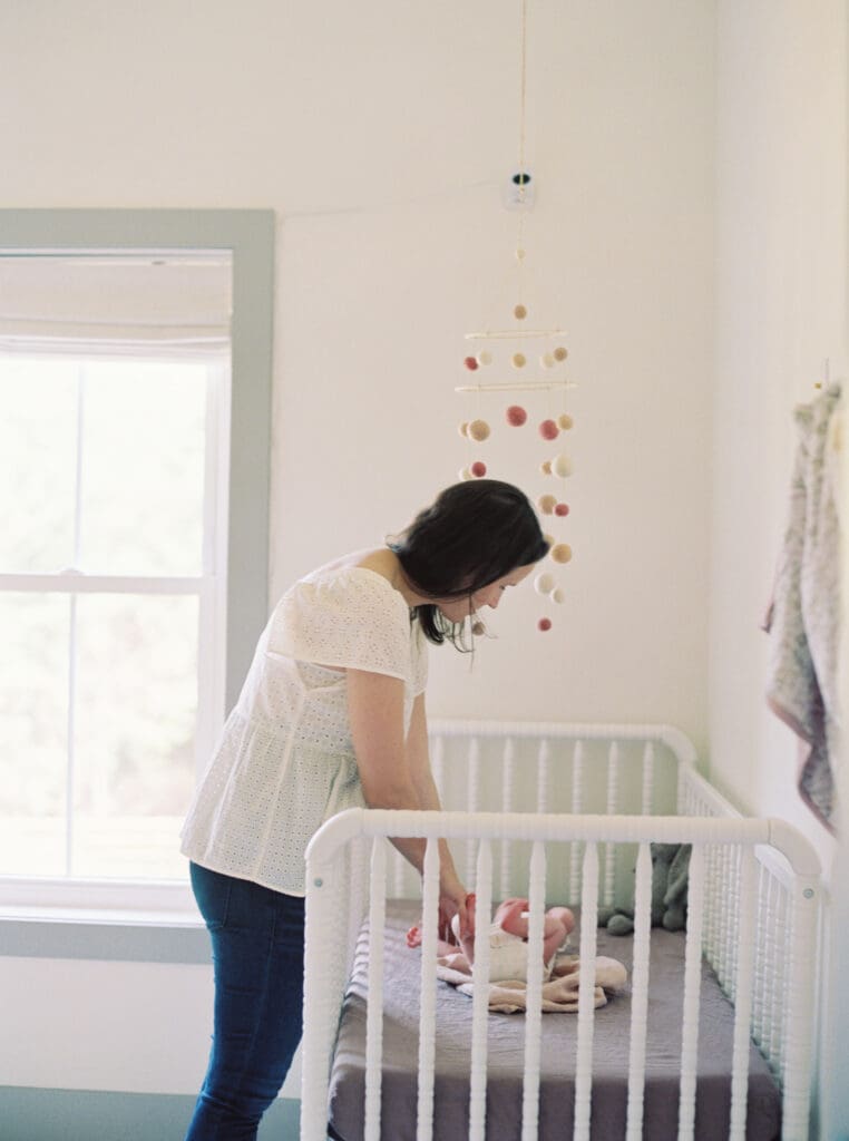 New mom holding her swaddled newborn during a lifestyle session — capturing one of my favorite newborn must-haves in use.